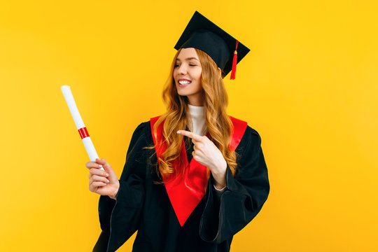 Happy graduate in a master's dress, with a diploma on a yellow background. Concept of the graduation ceremony