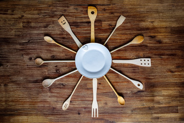 Wooden cooking spoons in shape of a clock on textured table, vintage style
