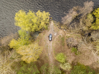 Black car on the shore of a forest lake. Aerial drone view.
