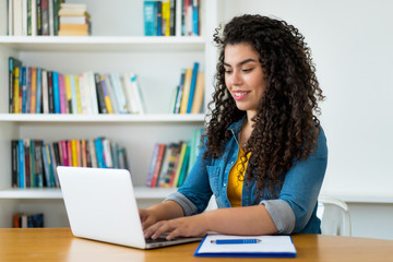 Laughing latin american woman in quarantine at computer