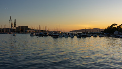 Flying airplane, sea cargo port on the island of Ciovo in the Adriatic at sunset, Croatia.