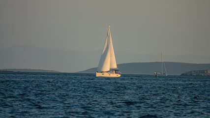 Fototapeta premium Sailing boat at sea, side view. Yacht is sailing in the Adriatic Sea against the backdrop of forested islands, Croatia.