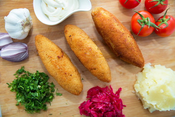 Ukrainian tradition food on a wooden board . Red cabbage sauerkraut in a small bowl . mashed potatoes . Mayonnaise, Garlic, Onion, Tomatoes. Chopped coriander.Chicken Kiev cutlets with parsley leaves.