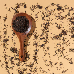 Dry Puer tea leaves in a wooden spoon on a beige background,hard light