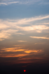 Beautiful orange sunset or sunrise with clouds. Colorful dramatic sky. Twilight bright sky background. Vertical shot. 