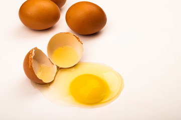 A broken chicken egg and scattered eggs on a white background. Close up.