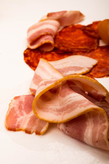 Slices of sausage and bacon on a white background. Close up.