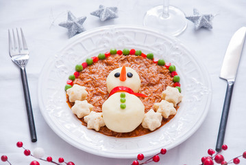 Snowman made from mashed potatoes and decorated meat stews and vegetables