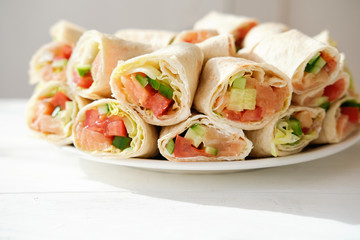 pita salmon rolls with cucumbers, tomatoes and letuce. Asian style rolls made with tortilla and fresh fish. delicious oriental appetizer. copy space for text. home made asian meal 