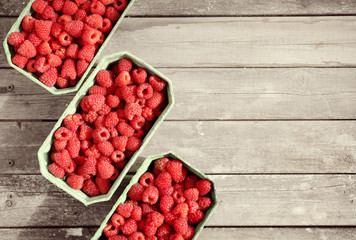 Fresh red raspberries in craft stalls, containers. on a wooden rustic old background. Top view of ripe berries. Autumn harvest.