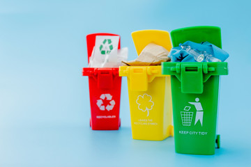 Yellow, green and red recycle bins with recycle symbol on blue background. Keep city tidy, Leaves the recycling symbol. Nature protection concept