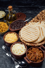 Top view of typical Latin American food. Group of arepas and different types of ingredients to fill them