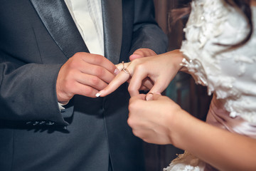 Obraz na płótnie Canvas putting on wedding rings in the church