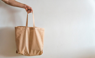 Eco bag in man's hand isolated on white background. Shopping, delivery concept with copy space.