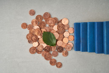 pile of coins with a green leaf and blue stairs