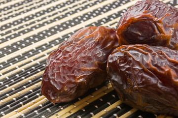 Big luxury dried date fruit on the bamboo mat, kurma ramadan kareem concept, close up.