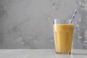 Fruit protein shake on a white wooden table. Fresh milkshake with passion fruit. A glass of protein shake.