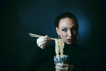 Beautiful girl eats noodles doshirak.
Studio photography, filter stylized photography