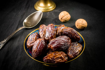 Big luxury dried date fruit in bowls on the dark surface, kurma ramadan kareem concept, close up.