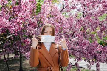 A young girl takes off her mask and breathes deeply after the end of the pandemic on a Sunny spring...
