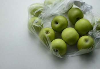  Green little apples in a plastic bag on a white background. Free space for text.