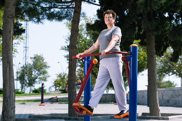 Naklejka premium Aged woman doing sport exercises on sport ground.