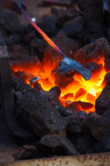 blacksmith furnace with burning coals, tools, and glowing hot metal workpieces
