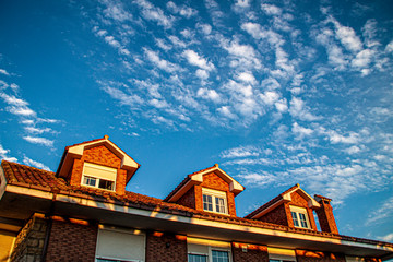 Amaneciendo, plano contrapicado de edificio con tres buhardillas, fondo cielo. © isabelgalán