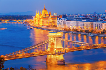 Fototapeta na wymiar Budapest, Hungary. Night view on Parliament building and Chain Bridge over delta of Danube river. Picturesque view of illuminated night European capital city.