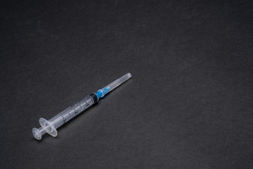Syringe on a matte black background. Copy space. Dark mode. Medical equipment