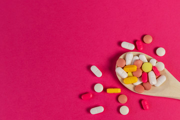 Mixed medicine pills, tablets on wooden spoon on pink background. Different pills and tablets. Health care. Top view. Space for text. Copy space. New image. Pharmaceutical pills and tablets. Closeup