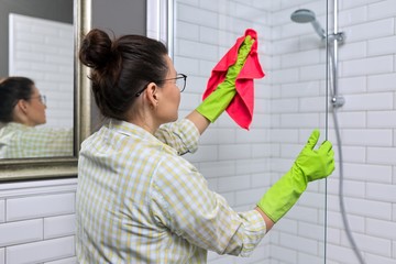 Female cleaning polishing shower glass with a washcloth with microfiber