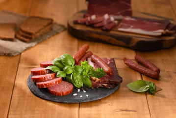 Ham and smoked sausage cutting on a slate plate.