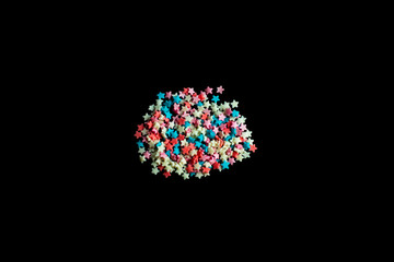 multicolored confectionery sprinkle in the form of stars on a black background