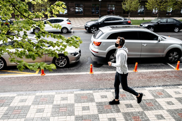 Keep yourself in shape during quarantine. Athletic young man is jogging in a protective mask. Healthy lifestyle concept