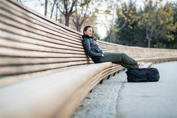 Side view of woman sitting on a bank with trees in background