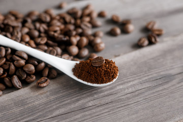  white ceramic spoon with ground coffee on a wooden background Fried Arabica grains