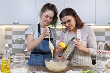 Mother and teenager daughter cook together at home in kitchen