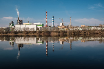 pipes of woodworking enterprise plant sawmill near river. Air pollution concept. Industrial...