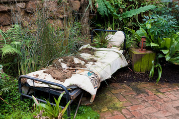 Very old metal bed and bedside table among the thickets