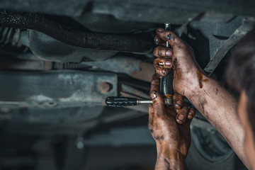 dirty hands of a technician while repairing a car