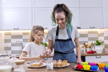 Kids sprinkling decorating cakes with white sugar powder