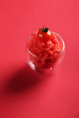 Cherry tomato refreshing sorbet granita in drinking glass over on red background Summer refreshing meal.