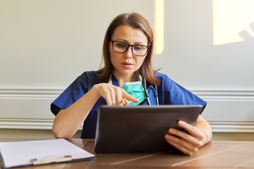 Female doctor counseling, helping patient online, medic using digital tablet for video call