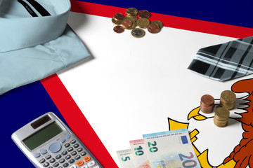American Samoa flag on minimal money concept table. Coins and financial objects on flag surface....