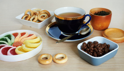 Cup of tea, fruit jelly, chocolate covered raisins, ring-shaped cracknel