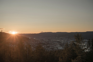 Sunset behind mountains over city scape.