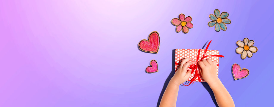 Little Boy Making A Gift Box With Flowers And Hearts Drawings Overhead View