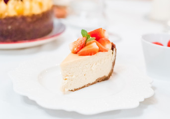 Fresh strawberry cheesecake on a ceramic plate on a white festive table