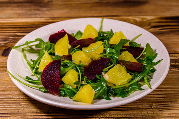 Salad with arugula, orange and beetroot in a ceramic plate